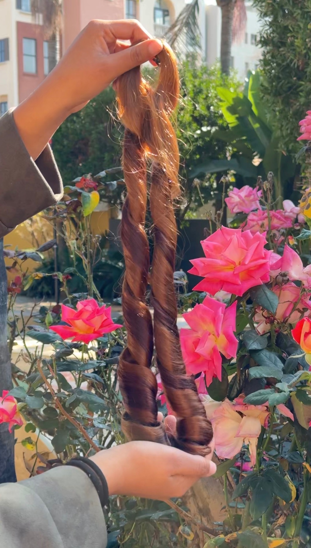 Hand holding twisted water wave hair strands in sunlight
