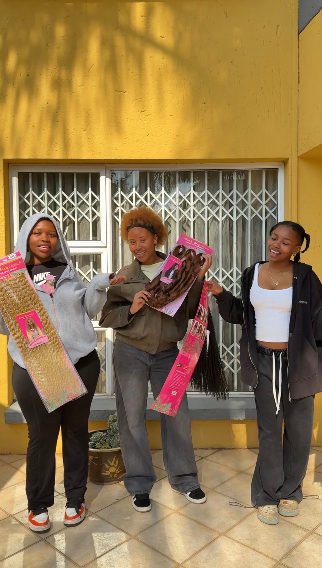 Three customers holding packs of Lovely Lady Fashion hair outside
